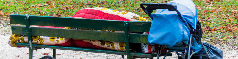 Auf einer Parkbank hat sich ein Obdachloser zum schlafen niedergelegt
