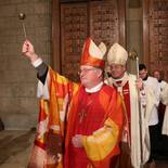 Der neue Bischof besprengt sich und die Gemeinde mit Weihwasser