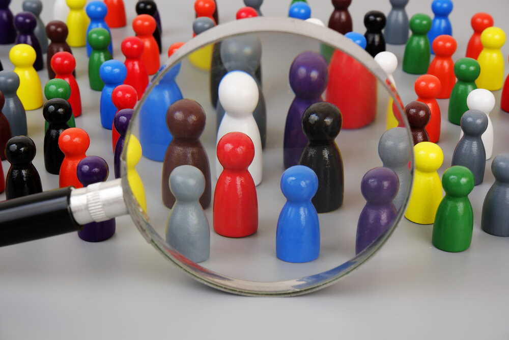Demografie / istockphoto / Valerii Evlakhov Spielfiguren mit einer Gruppe, die durch eine Lupe betrachtet wird