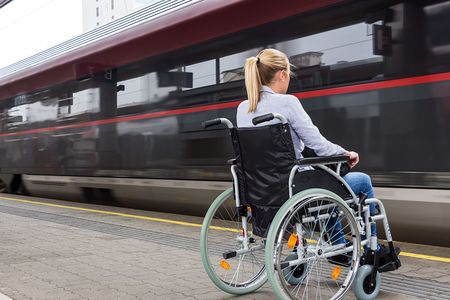Frau im Rollstuhl vor einfahrendem Zug
