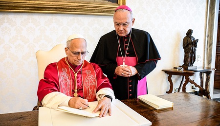 Papst Leo XIV. unterzeichnet das Apostolische Schreiben 'Dilexi te' (dt. Ich habe dich geliebt) am 4. Oktober 2025 im Vatikan. Hinter ihm steht Erzbischof Edgar Robinson Peña Parra, Substitut des Vatikanischen Staatssekretariats.