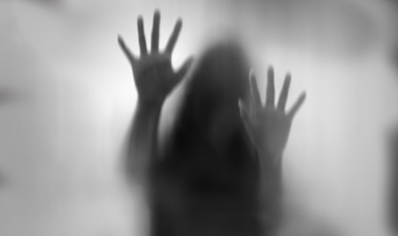 Horror woman behind the matte glass in black and white. Blurry hand and body figure abstraction.