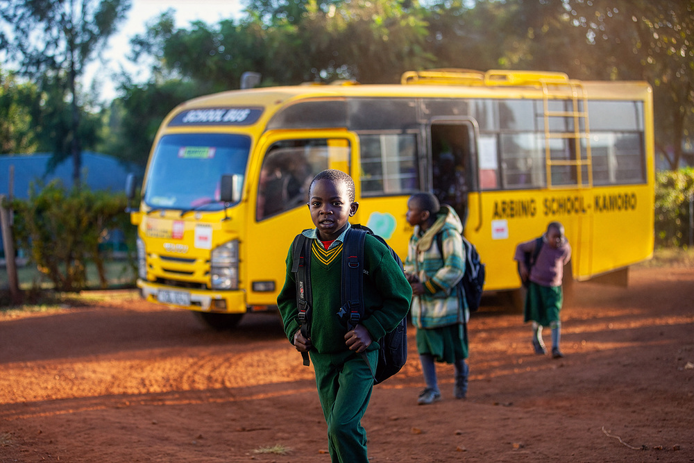 Kind in Afrika vor einem Schulbus / Christoph Haslinger-Galipeau MIVA: Christophorus-Aktion 2026 unterstützt Bildung mit Schulbussen